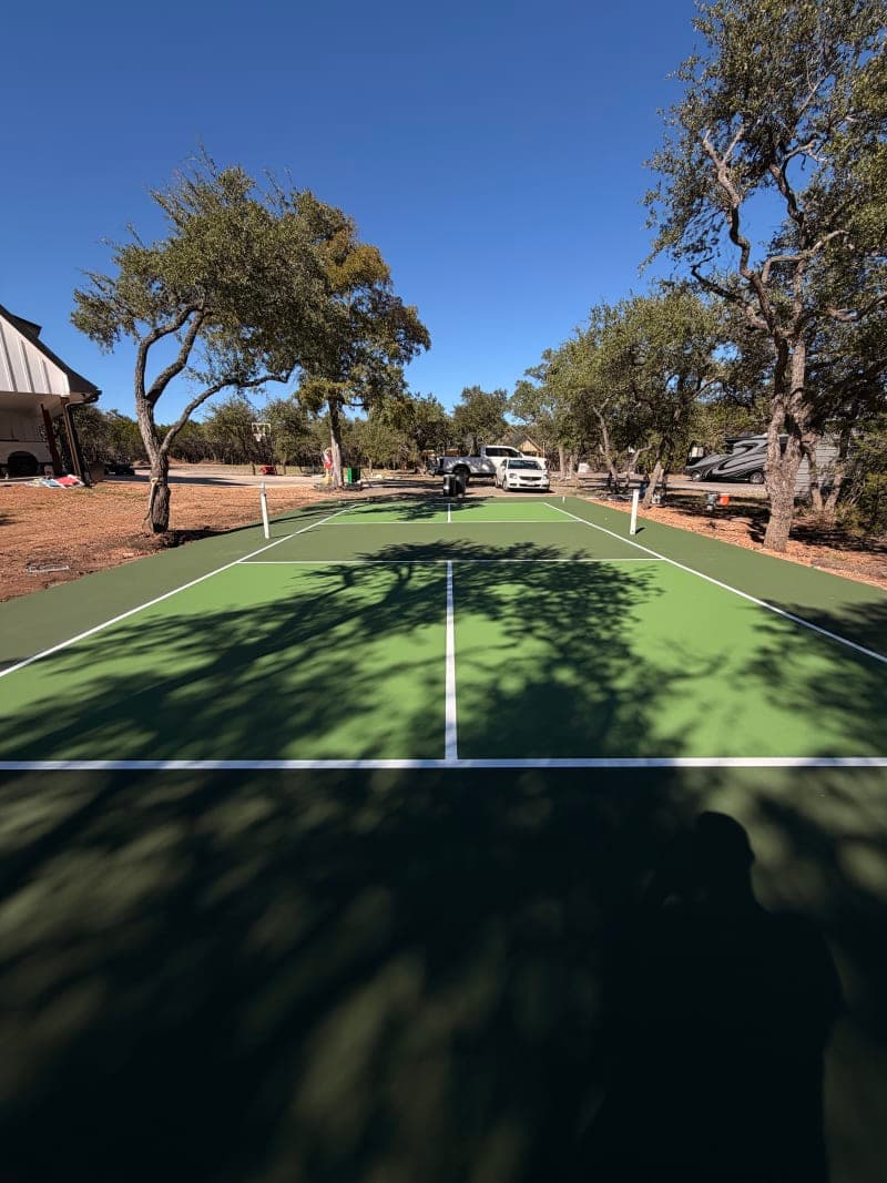 Two-color residential backyard court resurfacing with blue and green custom design in Wimberley Texas