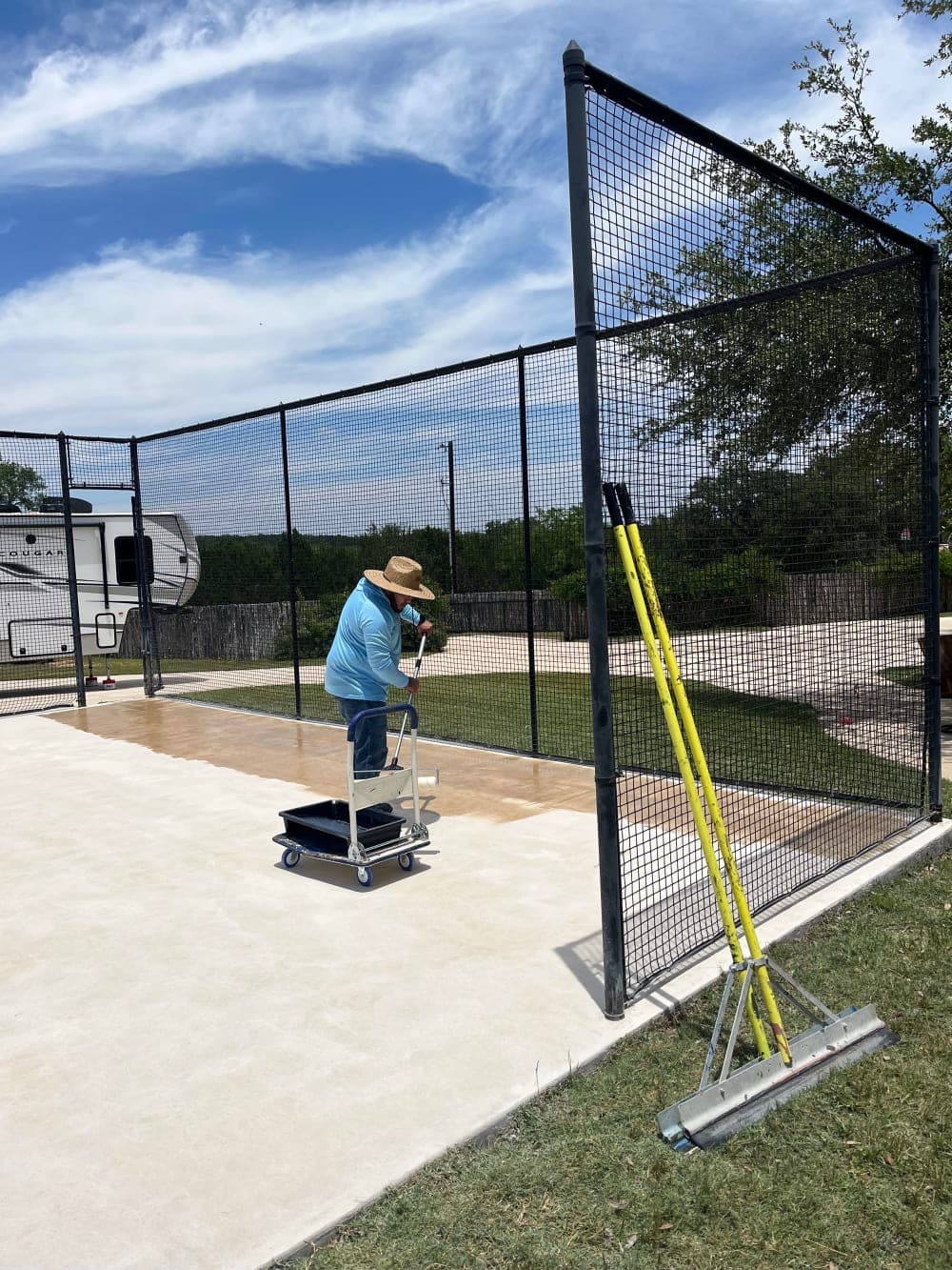 Crew member applying the primer coat during the court resurfacing in Wimberley, Texas