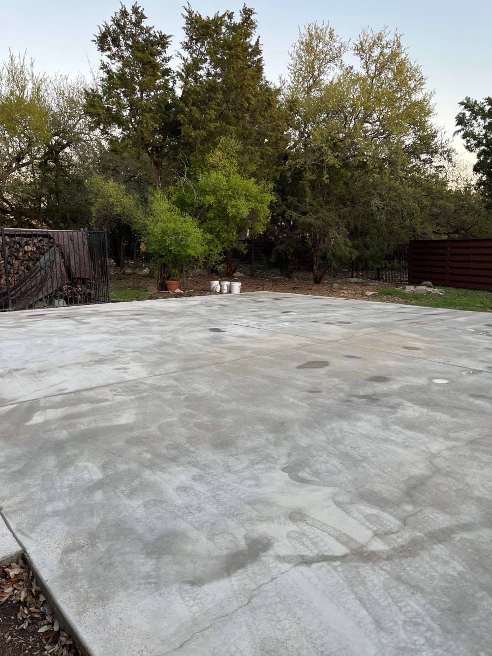 Bare fresh concrete slab in a wooded backyard before court surfacing in Georgetown, Texas