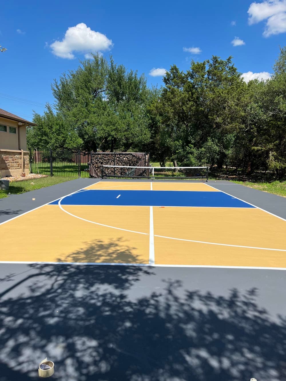 Finished blue and gold multi-sport basketball and pickleball court with fresh white striping in Georgetown, Texas