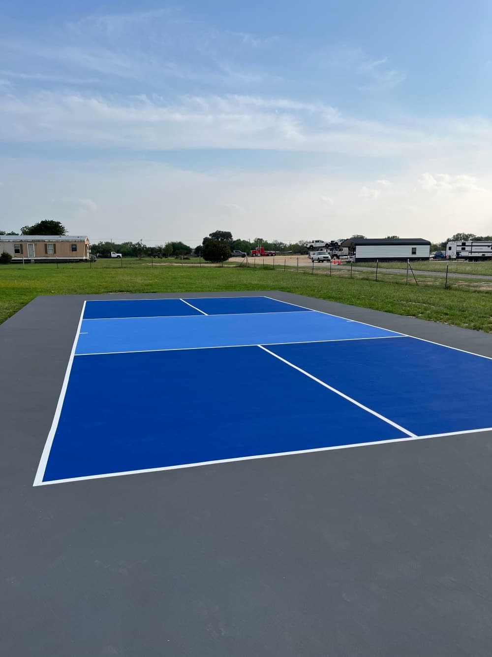 Finished tournament-blue pickleball court with gray surround and white striping near San Antonio, Texas