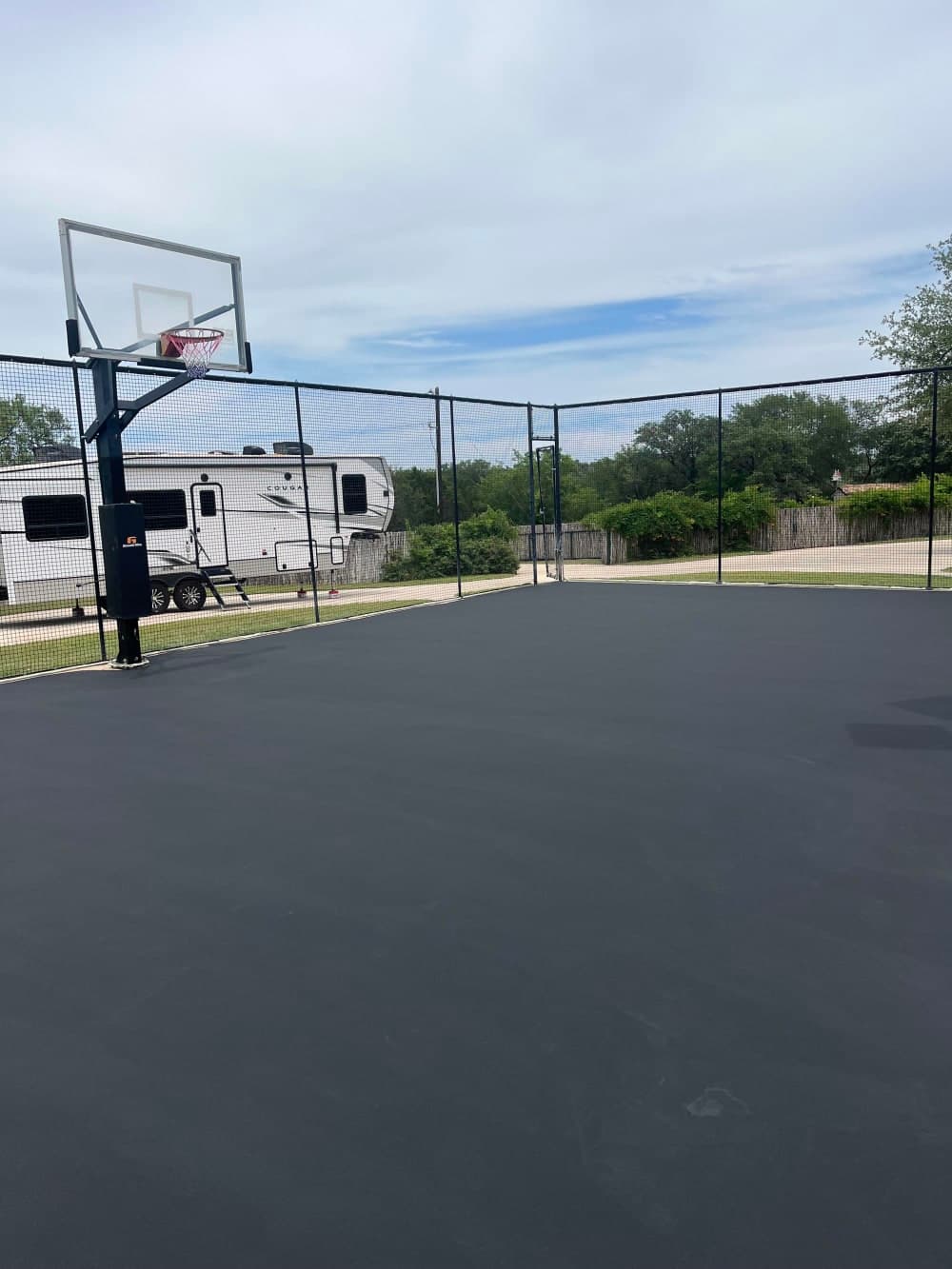 Black acrylic base coat applied over the prepped court in Wimberley, Texas