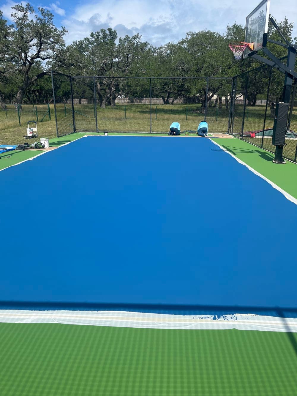 Crew applying the blue color coat and cutting in along the fence in Wimberley, Texas