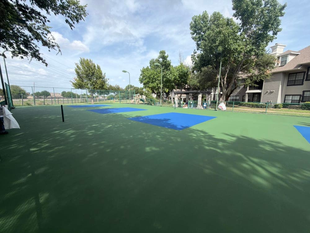 Green surround and blue pickleball color zones laid down over the resurfaced court before final striping in Richardson, Texas