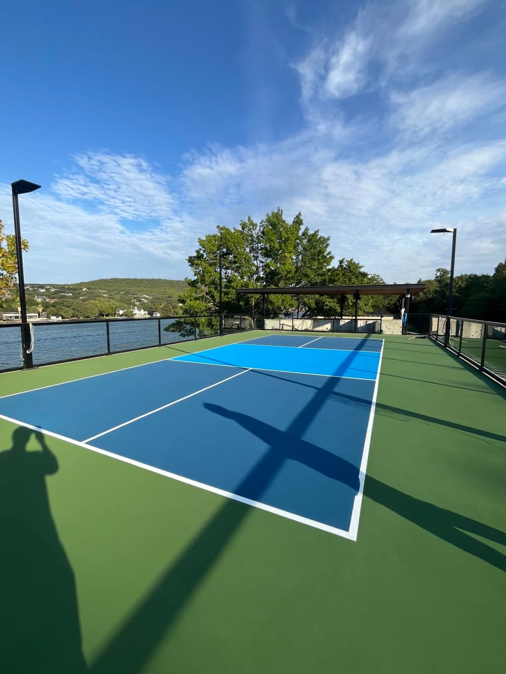 Finished rooftop pickleball court with a covered pavilion and Lake Austin hills in the background in Austin, Texas