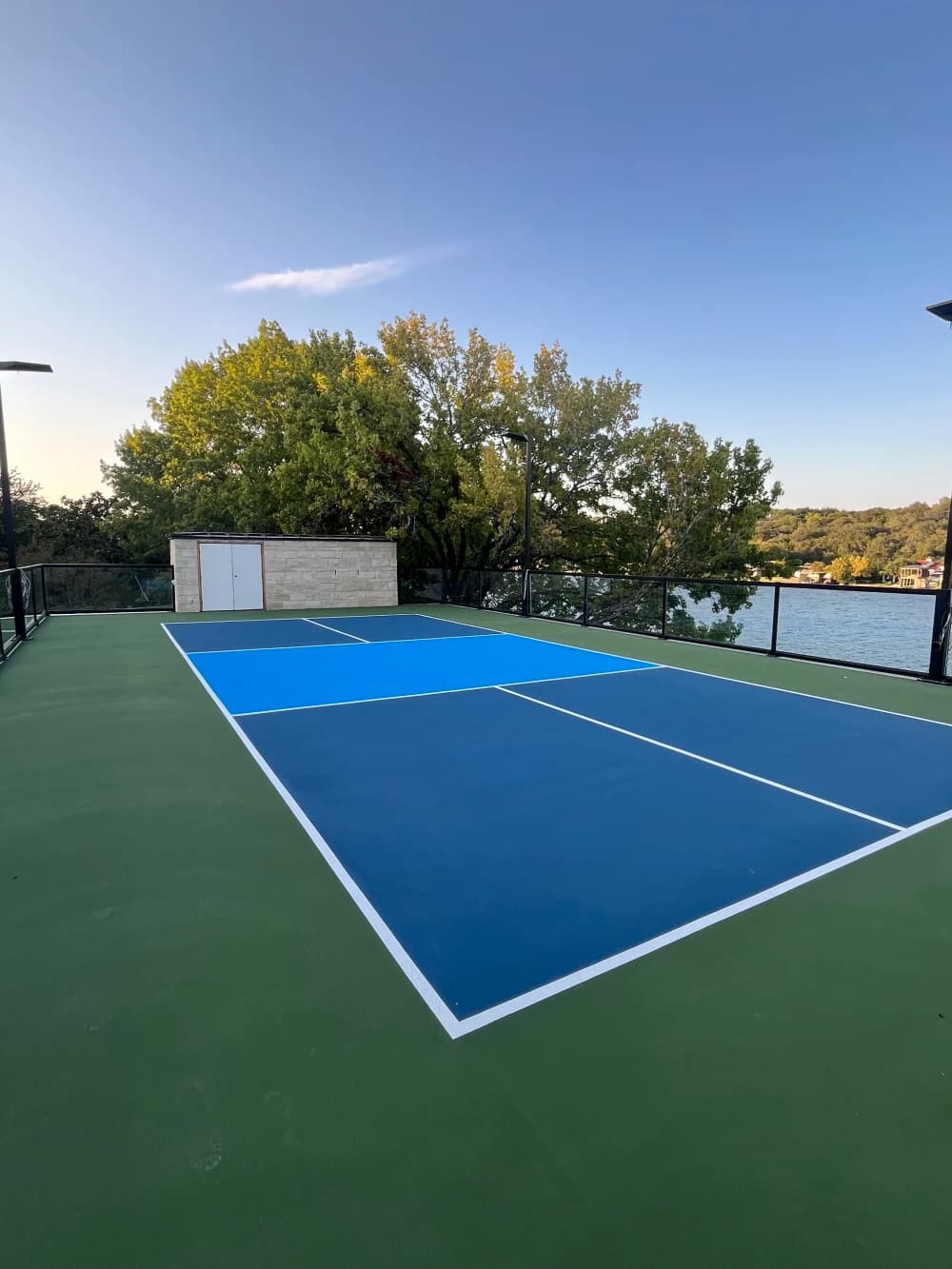 Finished rooftop pickleball court with navy playing boxes, light blue kitchen and white lines on Lake Austin, Texas