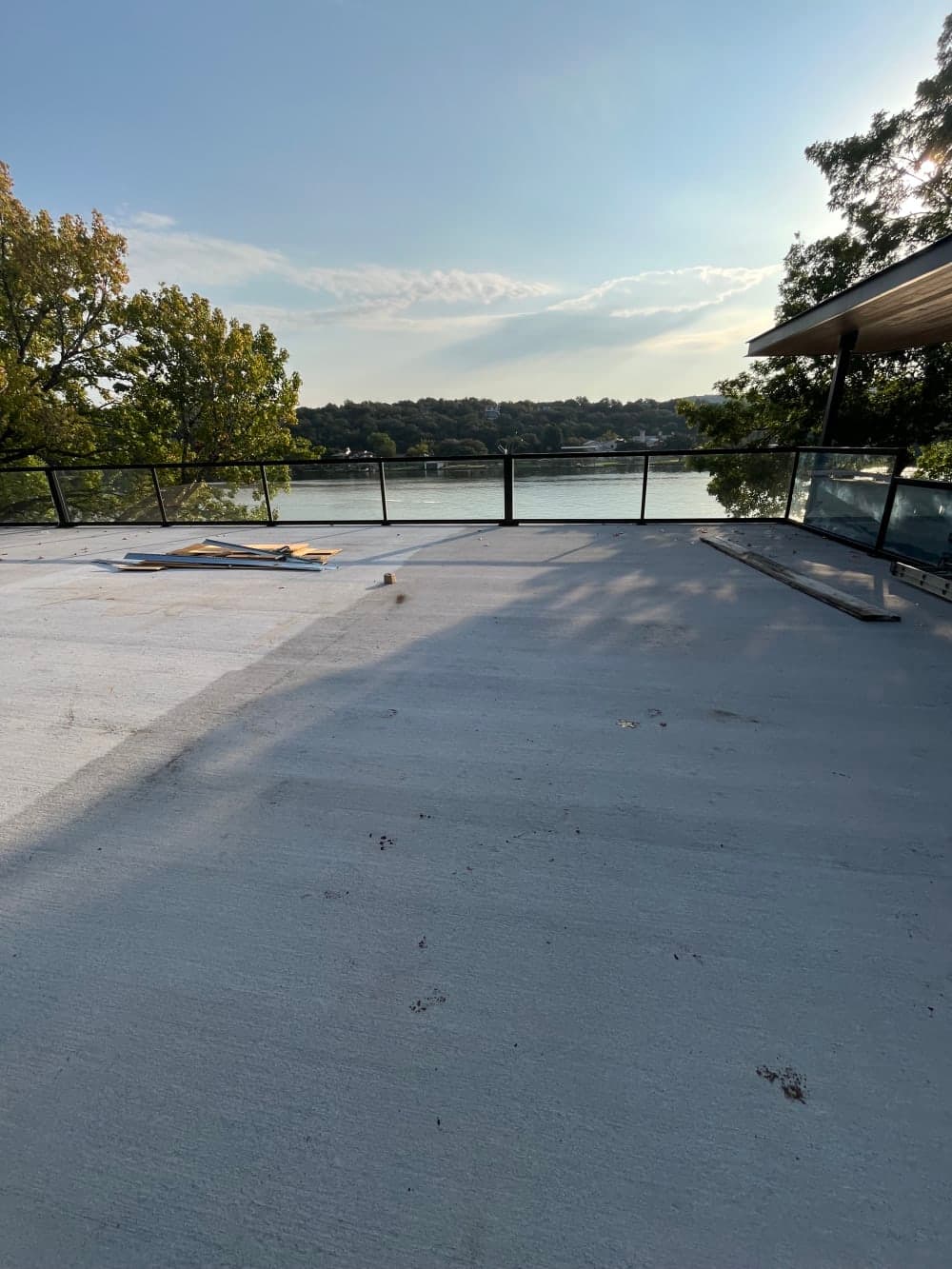 Bare concrete roof deck with glass railing overlooking Lake Austin before pickleball court surfacing in Austin, Texas