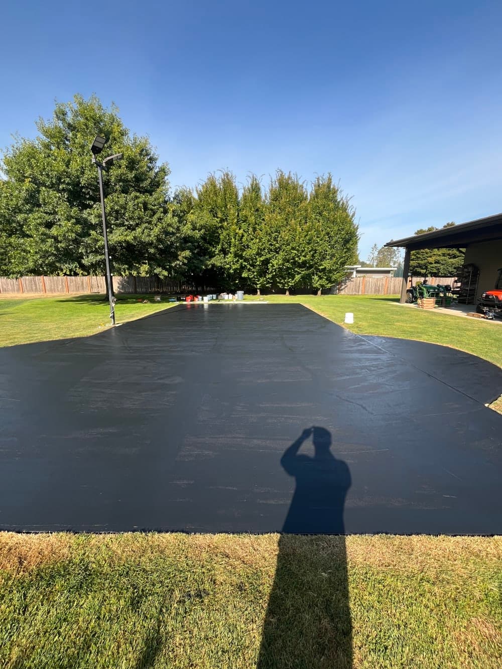 Black acrylic resurfacer coat applied across the full concrete court in Sumner, Washington