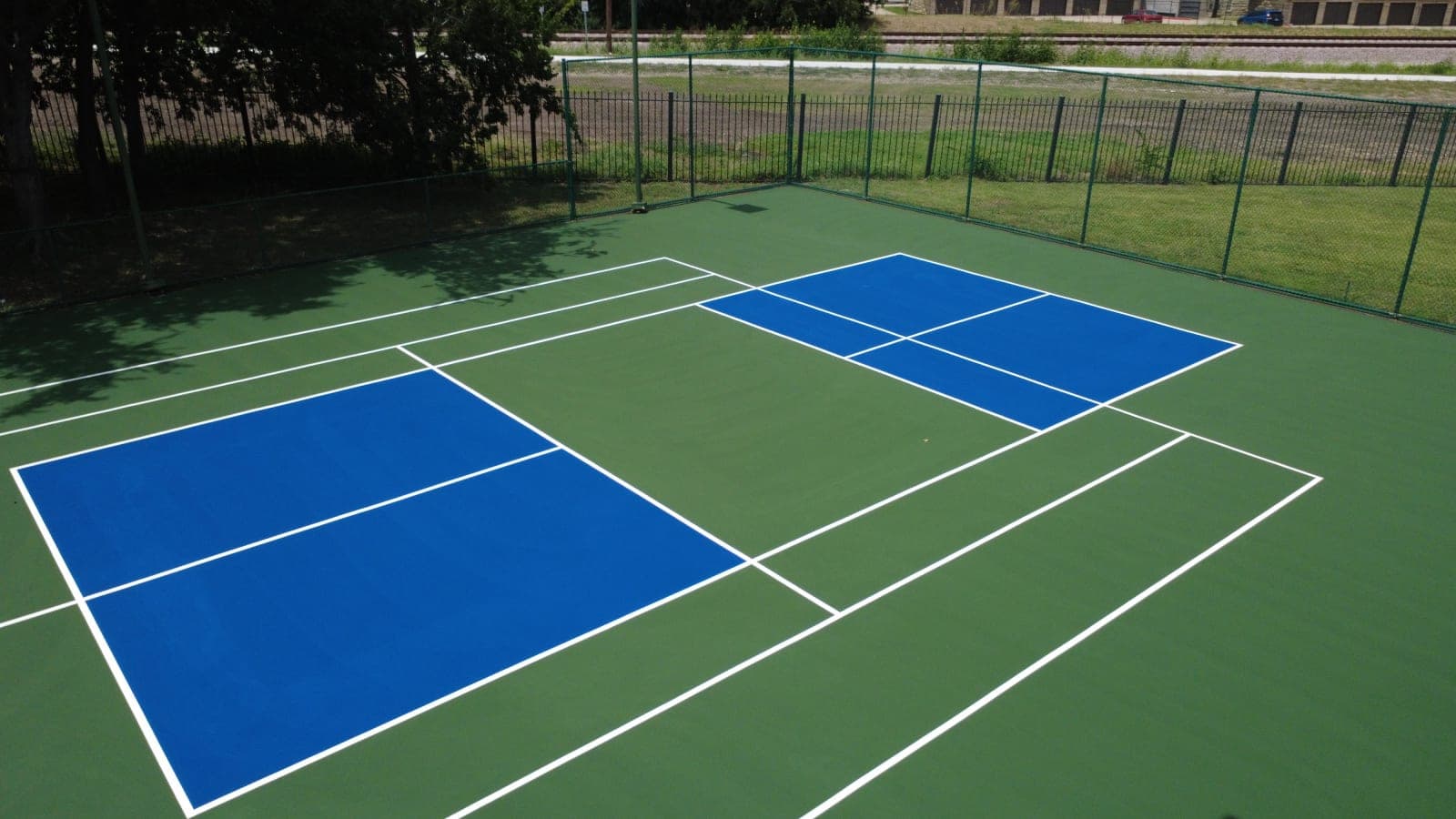 Aerial drone view of a finished green and blue pickleball court conversion with crisp white lines in Richardson, Texas