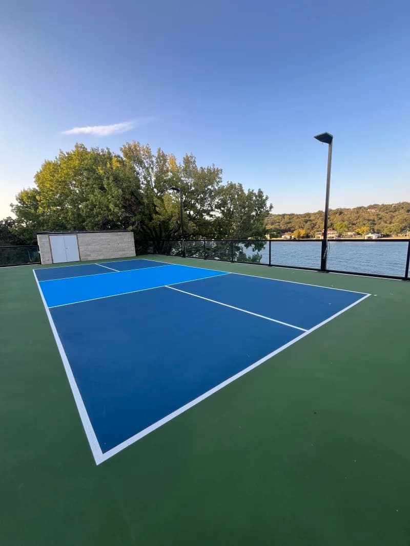 Finished navy and light blue rooftop pickleball court with a green surround overlooking Lake Austin in Austin, Texas